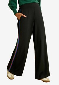 Zwarte broek met wijde pijpen en zijzakken, voorzien van een multicolor streep langs de buitennaad. Gemaakt van zacht materiaal met een gladde textuur.