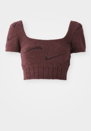 Lilla cropped top med et struktureret stof, firkantet halsudskæring, korte ærmer og ribbet kant, med subtile mørke mønstre gennemgående.