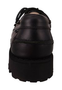Zapato de cuero negro visto desde atrás, con forma redondeada, superficie texturizada, detalles de costura y una gruesa suela de goma negra.