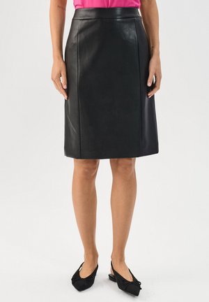 Gonna a matita nera in pelle con una texture liscia e una vestibilità sartoriale. Presenta una vita alta e un design al ginocchio, abbinata a scarpe nere slip-on.
