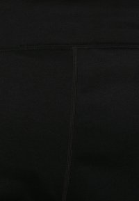 Leggings negros hechos de una mezcla de algodón elástico, con costuras planas y una textura lisa y mate sin patrones ni detalles adicionales.