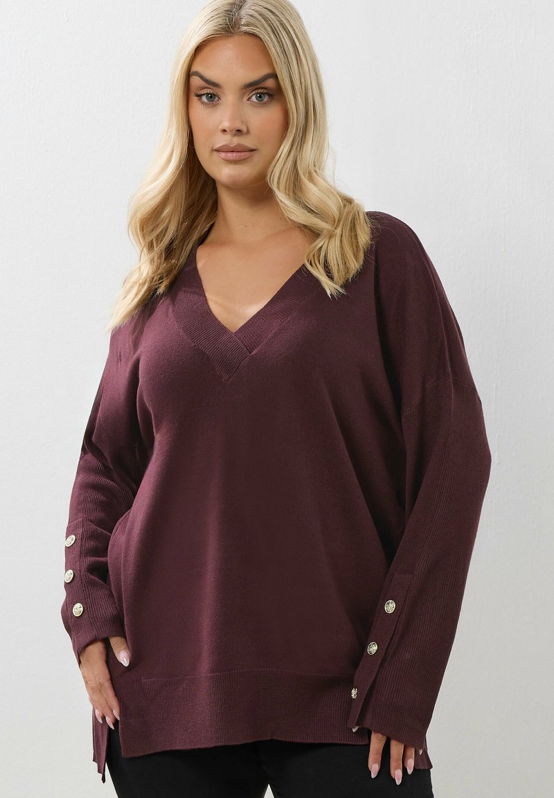 Bordeaux V-ringad tröja med långa, lösa ärmar som har knappdetaljer vid ärmsluten, tillverkad av mjukt, strukturerat stickat tyg.