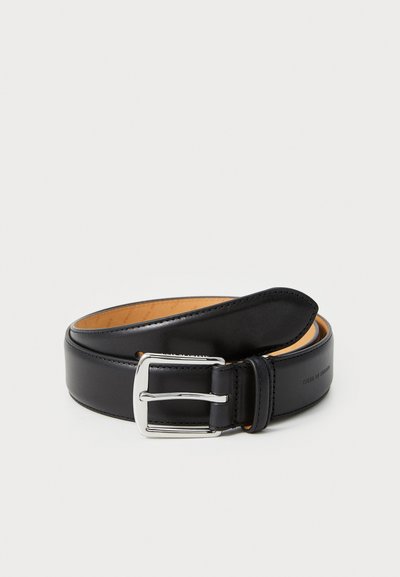 Cintura in pelle nera con una superficie liscia, fibbia in metallo argentato e fodera interna color tan. Presenta diversi fori per la regolazione.
