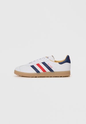 Scarpe da ginnastica bianche con strisce rosse e blu navy, suola in gomma, collo imbottito e marchio "GAZELLE" in rosso sul lato esterno.