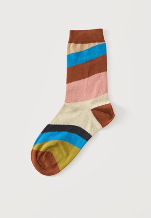 Chaussette longueur mollet avec des rayures horizontales marron, beige, bleu, rose, noir et moutarde sur fond blanc.