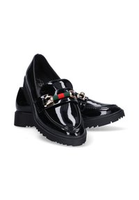 Mocasines de charol negro con suela gruesa, que cuentan con una hebilla en tono dorado y un detalle en la correa de rayas verde-rojo-verde.