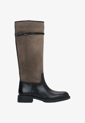 Botte à hauteur de genou avec une partie inférieure en cuir noir et une partie supérieure en daim brun, présentant un design épuré et une sangle en cuir noir autour du mollet.