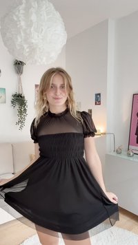 Fekete ruha áttetsző felsőrész és rövid puffos ujjakkal. Ráncos nyakkivágás és gumírozott derék. Folyékony szoknya könnyű textúrával.