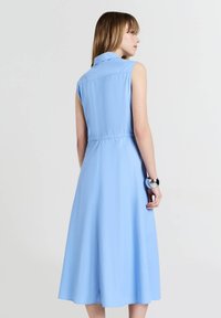 Helles blaues ärmelloses Kleid mit Kragen, tailliertem Bund und schwingendem Rock. Glattes Material mit schlichtem Design und ohne sichtbare Beschläge.