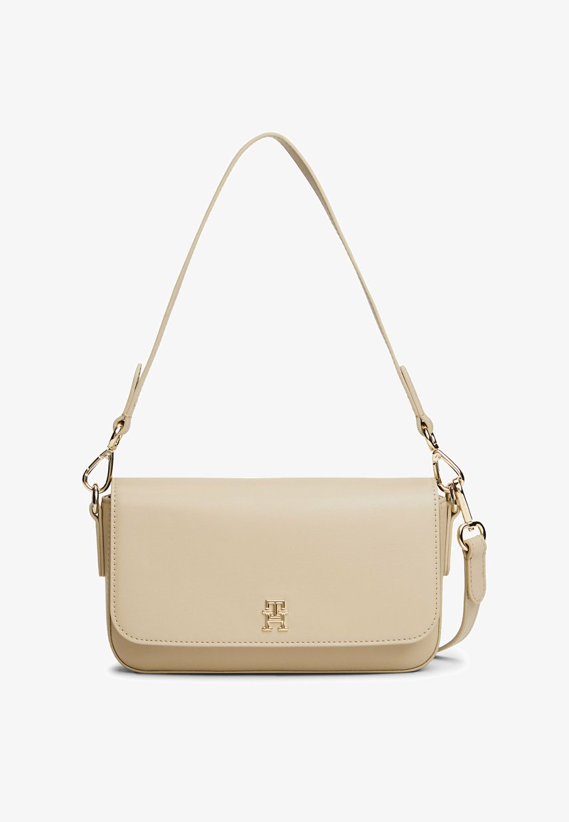 Borsa a tracolla in pelle beige con chiusura a pattina, dettagli in metallo dorato e tracolla regolabile. Presenta un logo decorativo sul davanti.