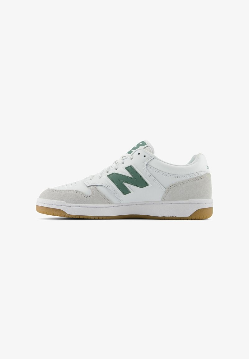 White athletic sneaker with green logo, suede accents, and a gum rubber outsole. Features perforations on the toe and padded collar.