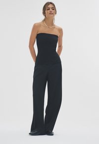 Zwarte strapless top met een aansluitend lijfje, gecombineerd met zwarte wijde broekspijpen. Soepele textuur, minimalistisch ontwerp en subtiele glans.