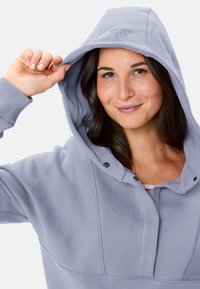 Helle lila Kapuzenpullover mit Kordelzug, gerippten Bündchen und vorderen Knopfdetails, aus einem weichen, strukturierten Stoff.