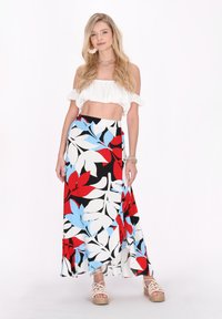 Bukseskørt med et blomsterprint i rød, blå og hvid på en sort baggrund. Toppen er en hvid crop-top med off-the-shoulder design.