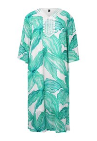 Witte kaftan met grote groene bladerenprint, met een V-hals en ingewikkelde borduursels rond de hals. Ruime pasvorm, met driekwart mouwen.