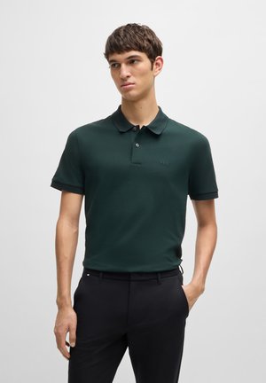Polo shirt vert foncé en tissu lisse, avec un col classique, une patte de boutonnage et un discret logo sur la poitrine.