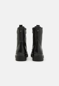 Schwarze Leder-Stiefeletten mit glatter Oberfläche, runder Zehenpartie, Zuglaschen an der Rückseite und einer robusten Gummisohle. Rückseitiger Reißverschluss.