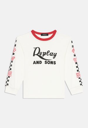 Fehér hosszú ujjú póló piros bordás gallérral. Jellemzője a "Replay AND SONS" grafika fekete és piros részletekkel, sakktábla mintázatú ujjakkal.