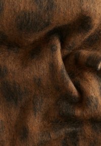 Tissu marron et noir à pois, avec une apparence douce et texturée de laine, présentant une surface froissée et légèrement surélevée.