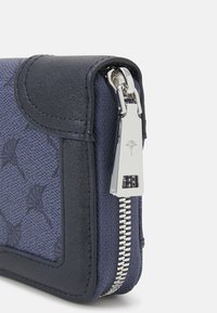 Portefeuille marine en tissu texturé avec des finitions en cuir lisse, doté d'une fermeture éclair argentée et d'un logo embossé sur le matériel.