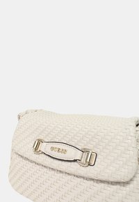 Borsa a tracolla bianca con pattina arrotondata, dotata di una placca con logo in metallo e accessori in argento. Superficie testurizzata con un evidente motivo di intrecci.