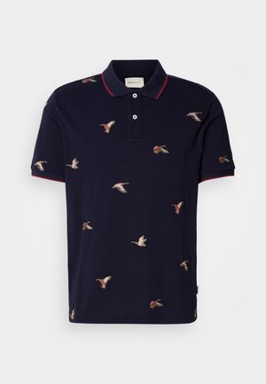 Mörkblå polo t-shirt med röd krage och ärmslut, prydd med broderade ankor i olika positioner över tyget. Tillverkad av bomull.