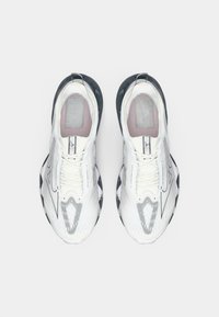 White athletic shoes with a mesh upper, contrasting black sole, unique pattern on the toe box, and reflective accents.