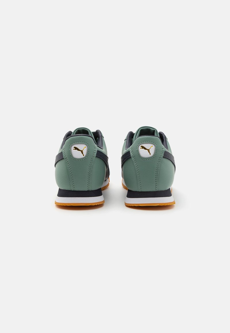 Grüne und marineblaue Sportschuhe mit einem schlanken Design, gummierter Sohle und goldener Logodetail am Fersenbereich. Obermaterial aus strukturiertem Leder.