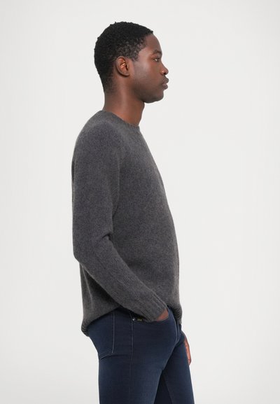 Grijze gebreide trui met een ronde hals, lange mouwen en een zachte textuur, gecombineerd met donkerblauwe slim-fit jeans.