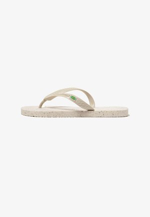 Chancla de goma beige moteada con correas texturizadas y pequeño logo verde y amarillo en la correa lateral.