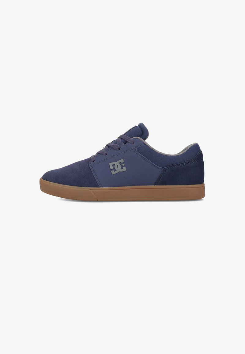 Navy blue sneakers with a smooth upper, suede material, brown rubber sole, and a "DC" logo on the side. Lace-up design with padded collar.
