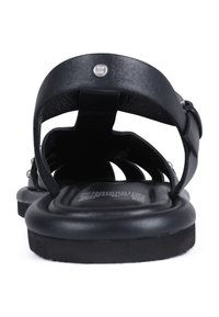 Sandalias de cuero negro con un diseño abierto, correas anchas y punta redonda. Presentan una plantilla texturizada y una suela suave y acolchada.