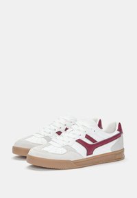 White sneakers with burgundy accents, featuring a textured suede toe, leather side stripes, and a gum rubber sole. Standard lace closure.