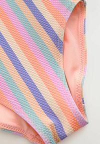 Gestreifte Badeshorts aus strukturiertem Stoff in Pastellfarben: Pfirsich, Lavendel, Minze und Hellrosa, mit glatter Innenauskleidung und Zickzacknähten.