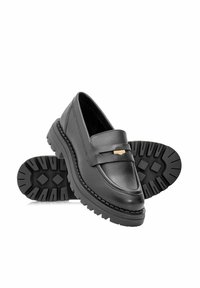 Czarne skórzane mokasyny z teksturowaną gumową podeszwą, z wyraźnym złotym akcentem w postaci paska i gładkim wzornictwem cholewki.