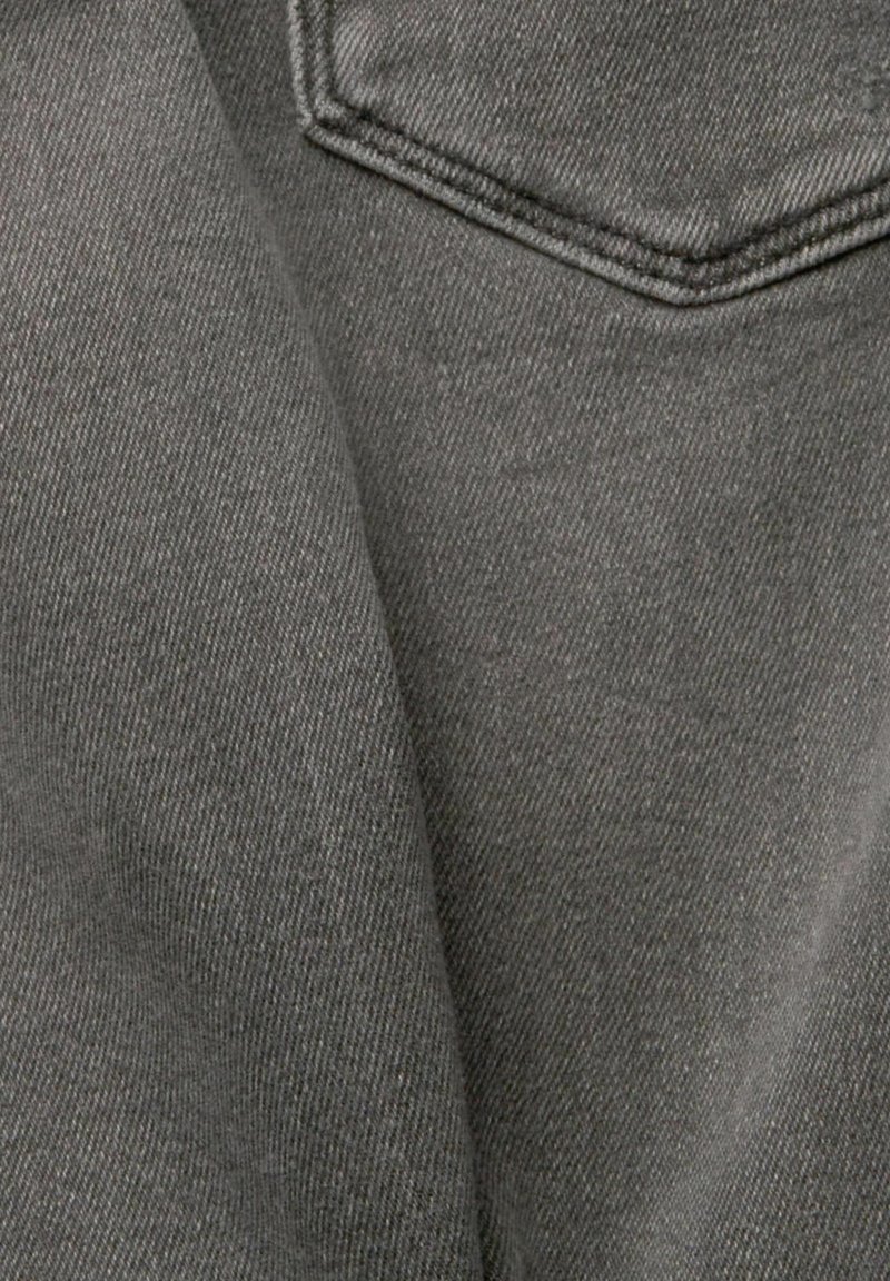Dunkelgrauer Denim-Stoff mit weicher Textur, der sichtbare Nähte und eine strukturierte Tasche oben rechts präsentiert.