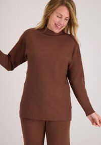 Bruine pullover trui met een hoge halslijn, lange mouwen en geribbelde manchetten; gladde textuur met een comfortabele pasvorm, gecombineerd met bijpassende broek.