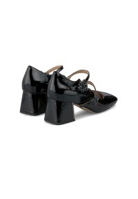 Chaussures à talon carré en cuir verni noir avec des pointes et des sangles réglables ornées de décorations en métal. Texture lisse et finition brillante.