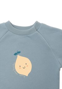Hellblaues Sweatshirt mit einem runden Zitronenmotiv in pastellgelb, lächelndem Ausdruck und grünem Blatthighlight. Der Text lautet "squishy lemon."