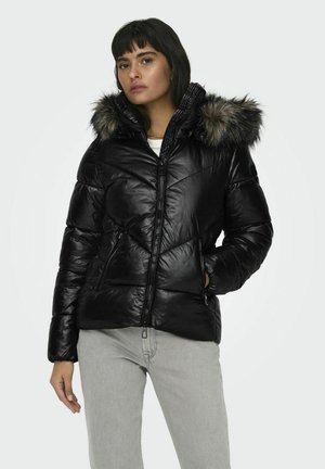 Chaqueta tipo puffer negra con capucha con borde de pelo sintético, diseño acolchado, cierre frontal con cremallera y bolsillos laterales. Material suave y brillante con una silueta ajustada.