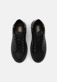 Black leather sneakers with lace-up design, padded tongue, logo on insole, and silver accents on the heel, featuring a smooth texture.