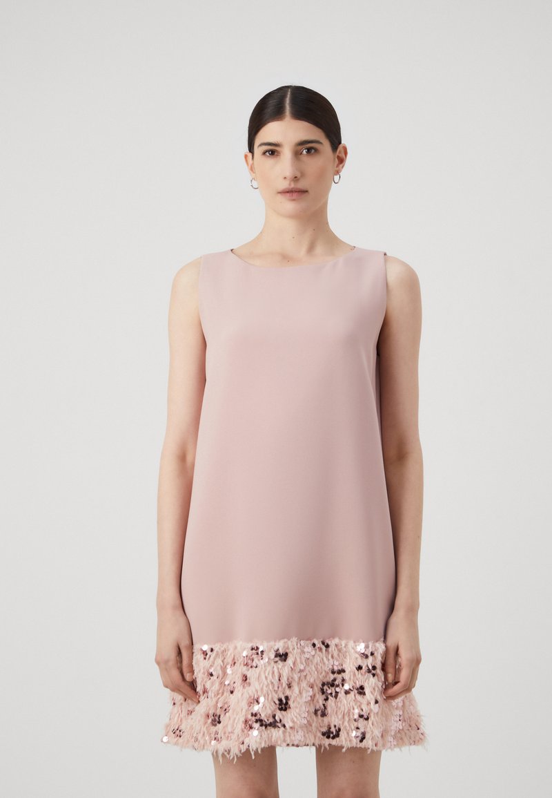 Um vestido rosa sem mangas com um topo suave e uma bainha de franjas texturizadas feitas de lantejoulas e fibras rosas, apresentando um decote redondo.