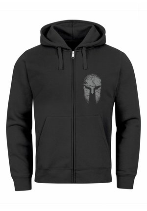 Black zip-up hoodie made of soft fabric, featuring a cracked skull design in gray on the left chest. Includes front pockets and drawstring hood.