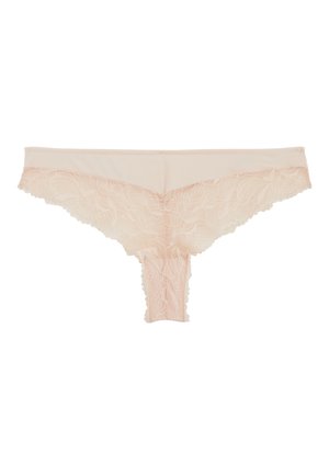Tanga pour femme en dentelle beige avec motif floral et bords festonnés, posé à plat sur un fond blanc.