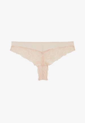 Tanga pour femme en dentelle beige avec motif floral et bords festonnés, posé à plat sur un fond blanc.