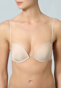 Beige padded plunge bra dengan tali tipis yang dapat disesuaikan. Tekstur halus dan desain kontur yang cocok untuk dipakai tanpa jahitan di bawah pakaian.