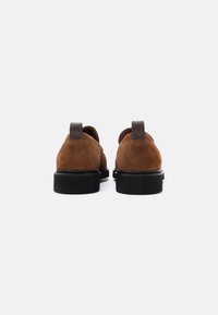 Brown suede shoes with a rounded toe, featuring a contrasting black rubber sole and brown leather accents at the heel and back.
