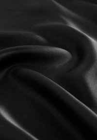 Tessuto di satin nero con una texture liscia e lucida, caratterizzato da pieghe morbide e delicate riflessioni che esaltano la profondità del materiale.