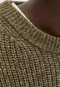 Žalias mezginys su tekstūriniu raštu ir ribota apykakle, su lengvais akcentais, įaudžiais į siūlą.