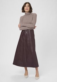 Pruuniriba turtleneck koos pika, tumeda burgundia nahkskjörtiga. Mudel kannab beezhseid teravade varvastega kingi.